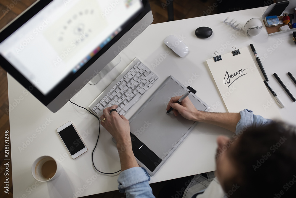 Aufkleber young male designer using graphics tablet while working with com