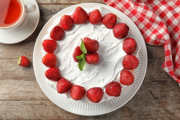 Delicious cake with strawberries on wooden table
