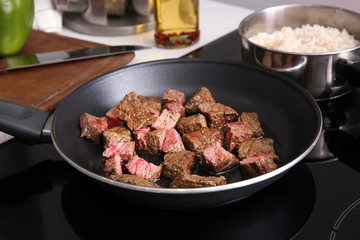 Frying pan with meat on stove