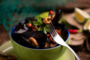 Boiled mussels in cooking dish on wooden background
