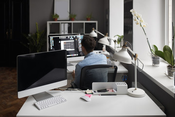 Young intelligent bearded man working at modern loft studio-offi