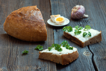 Bread with Fresh Parsley Leaves, Eggs, Butter and Garlic on Wooden Background