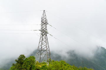 High voltage pole towers on the mountain in the fog and mist on forest. White background