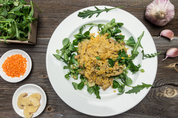 Lentils with Rocket Salad on White Plate wit Raw Ingredients on Wooden Background