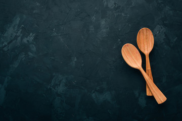 Wooden spoon On a black stone background. Top view. Free space for text.