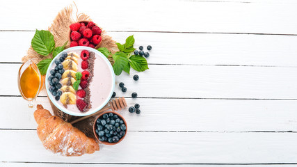 Yogurt with blueberries, raspberries and banana. In the plate. On a wooden background. Top view. Free space for text.