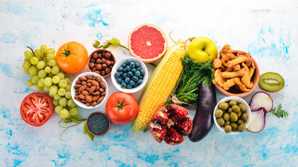 Healthy food on a white wooden table. Fresh vegetables, fruits, nuts, berries, mushrooms. Top view. Free space for text.