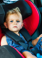 Portrait of cute baby boy sitting in car seat. Child transportation safety