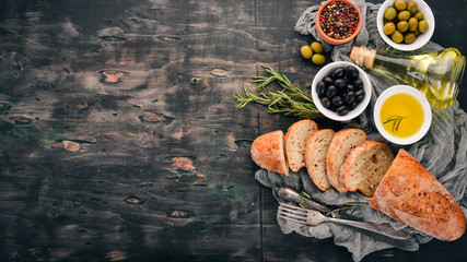 Olives and bread. Italian cuisine. On a wooden table. Top view. Free space for text.