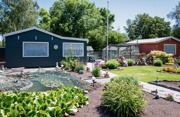 Garden shed with greenhouse and pond surrounded by a beautiful decorative garden