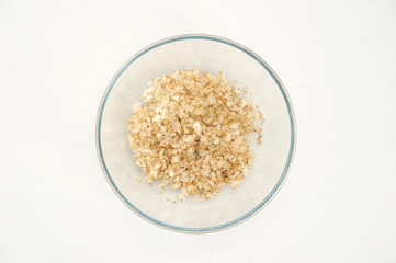 In a deep bowl, the onions are mixed with spices and fat. White background. Close-up. View from above.	