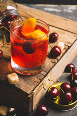 Old fashioned cocktail with cherry and orange peel. Selective focus.