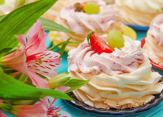 Obraz na płótnie Canvas Strawberry pavlova cake nests, meringue decoration on wood table with flowers.