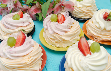 Strawberry pavlova cake nests, meringue decoration on wood table with flowers. Selective focus.