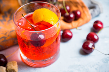Old fashioned cocktail with cherry and orange peel. Selective focus.