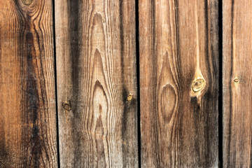 Bright brown textured old wooden boards background. Abstract closeup shot of dark and light lined wood country fence