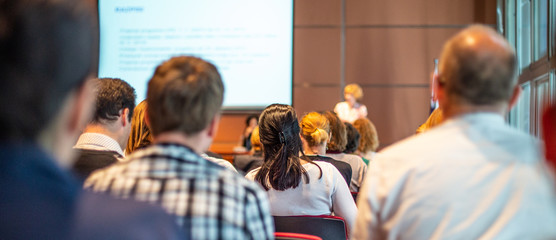 Business and entrepreneurship symposium. Female speaker giving a talk at business meeting. Audience...