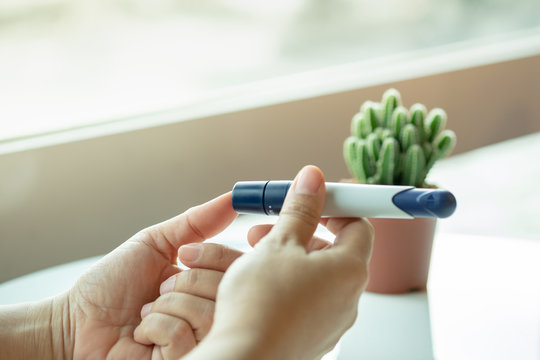 Close up of woman hands using lancet on finger to check blood sugar level by Glucose meter. Medicine, diabetes, glycemia, health care concept.