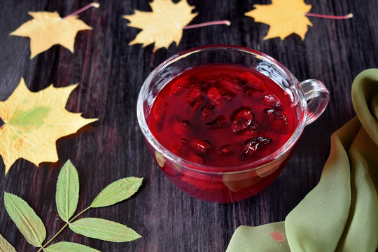Berry kissel in a glass cup surrounded by autumn leaves 