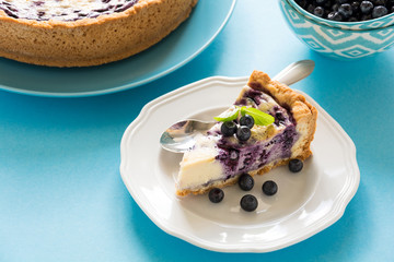 Tea time. Homemade blueberry cheesecake with ricotta cheese on blue paper background