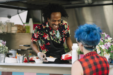 Smiling food vendor hands food to waiting customer