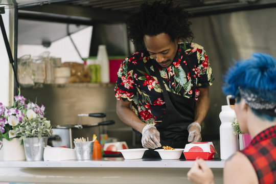 Smiling food vendor hands food to waiting customer