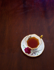 Royal Stafford Bone China tea cup and saucer with a red rose pattern, English Breakfast Tea, on a wood surface
