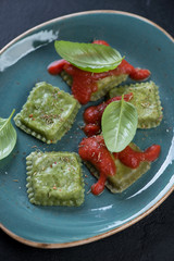 Close-up of ravioli with spinach and cheese served on a turquoise plate, selective focus