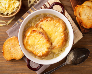 French onion soup with croutons and cheese on rustic wooden table