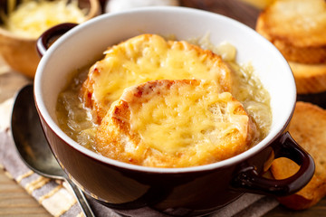 French onion soup with croutons and cheese on rustic wooden table