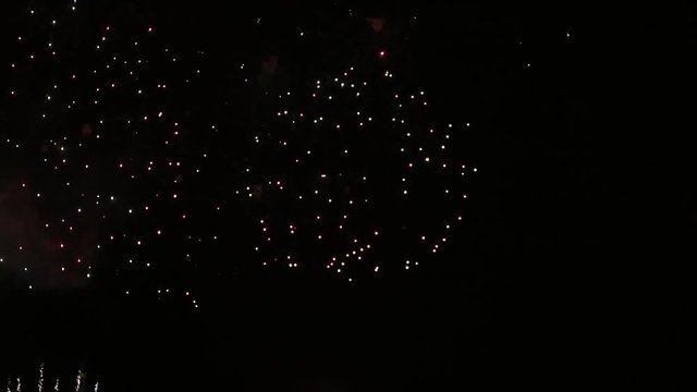 Exploding fireworks on the night sky, in slow motion video. Colorful rain showers of fireworks on the dark night background. Festive event accompanied by holiday salves. Holiday & pyrotechnic show.