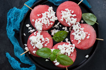 Obraz na płótnie Canvas Above view of round fresh watermelon slices on wooden skewers with cottage cheese, horizontal shot