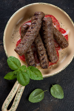 Above view of a serving pan with grilled cevapi or cevapcici sausages, vertical shot