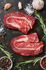 Beef raw steak on a dark rustic background with rosemary and spices. The view from the top,flat lay.