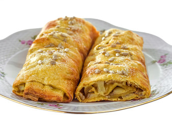 Apple strudel with cinnamon and sunflower seeds on a plate with a gilded edge. Selective focus.