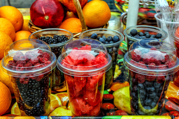 fresh organic berries: blackberries, raspberries, watermelon in transparent glasses on the table for sale.