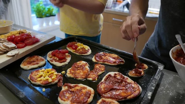 Tomato sauce and vegetables are put on small pizzas