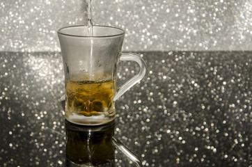 
Sirviendo la taza de té en el fondo de plata brillante
