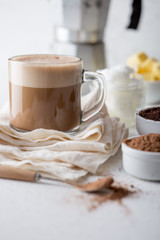KETOGENIC KETO DIET DRINK. Coffe and cacao blended with coconut oil. Cup of bulletproof coffe with cacao and ingredients on white background