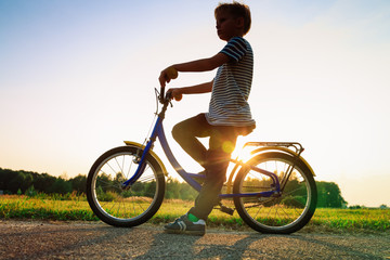 Fototapeta na wymiar little boy riding bike at sunset, kids sport