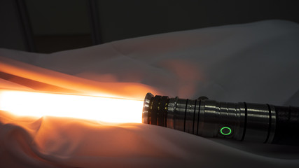 Activated lightsaber resting on fabric. Not as clumsy or random as a blaster. An elegant weapon for...