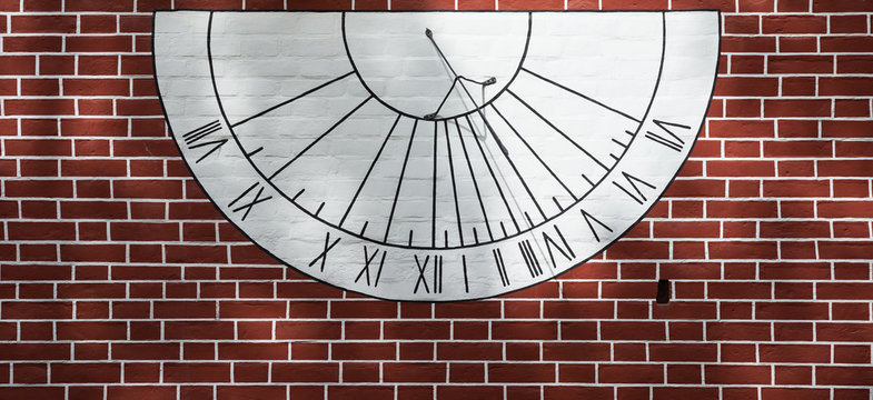 Sundial on the wall of an old red-brick house