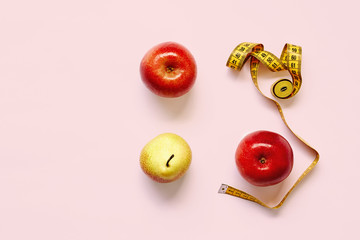 Measure tape and fresh fruits apples, pear on pink background. Loss weight, slim body, healthy diet concept
