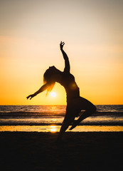 Silhouette of a happy beautiful dancer girl at sunset