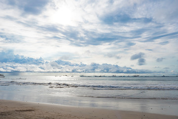 An ocean scene with boats moored off shore and a very cloudy sky. A grey and blue serene landscape.