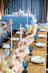luxury dinner Banquet in the restaurant. Beautiful and exquisite decoration of the wedding celebration. Banquet served table with a beige pink tablecloth, plates and candlesticks with candles.