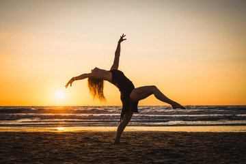 Silhouette of a happy dancer girl jumping the sunset