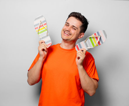 Young handsome man in orange t-shirt with sandals. Studio image on white background