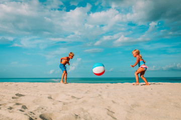little girl and boy play ball on beach