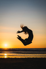 Silhouette of a happy dancer girl jumping the sunset